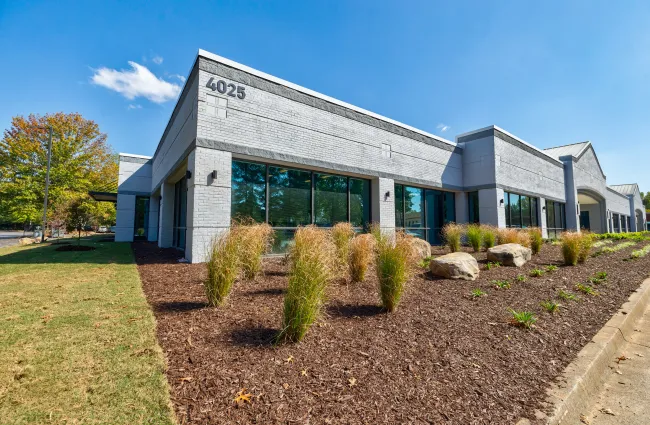 Modern single-story commercial building with large windows, landscaping, and the number 4025 on the corner.