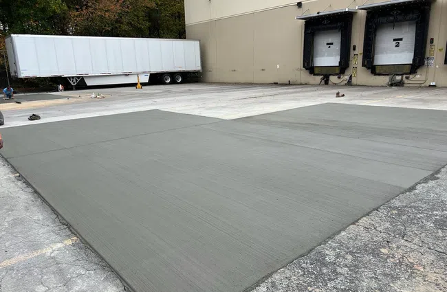 Freshly poured concrete slabs drying near loading dock bays with a white trailer in the background
