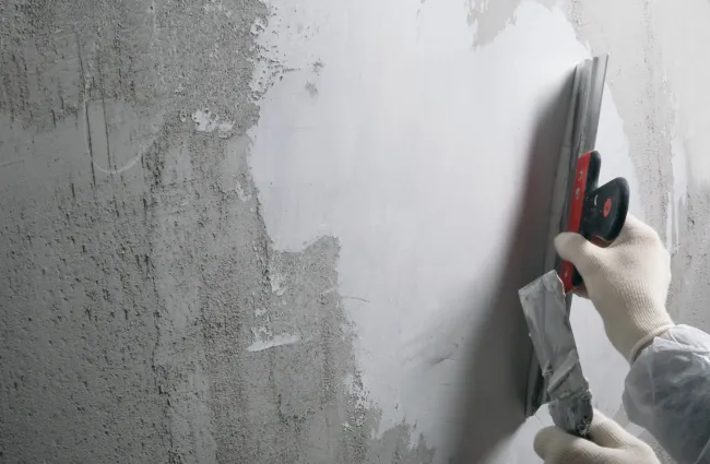 a person holding a red and black object in front of a white wall