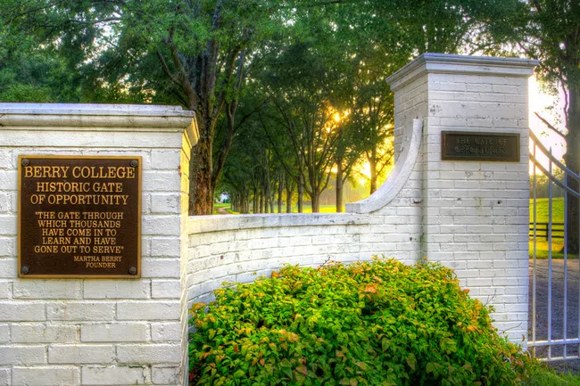 Berry College's Historic Gate of Opportunity at sunrise, showcasing scenic trees and inviting entrance.