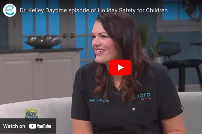 Dr. Kelley smiling during a daytime TV interview about holiday safety for children in a cozy studio setting.