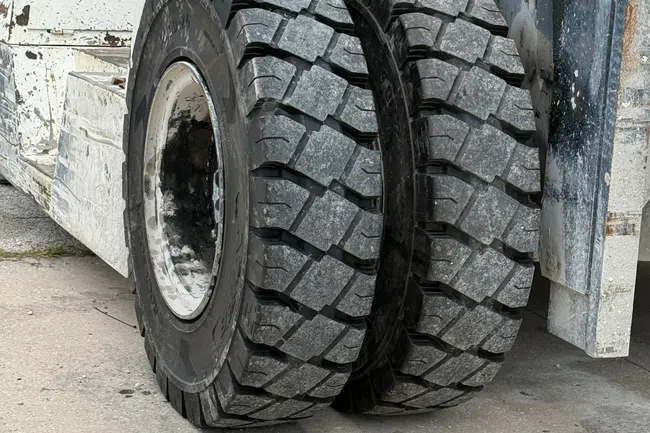 Close-up of dual heavy-duty tires on an industrial forklift with rugged tread patterns on concrete ground.