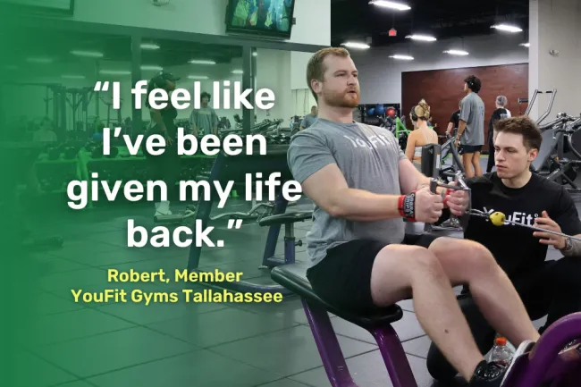 Man exercising on rowing machine with trainer assisting in a busy gym setting with motivational quote overlay.