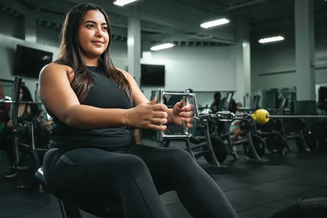 Woman using gym equipment for strength training in a modern fitness center.