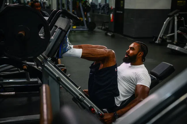 Man with beard and white shirt working out on a leg machine in YouFit Gyms.