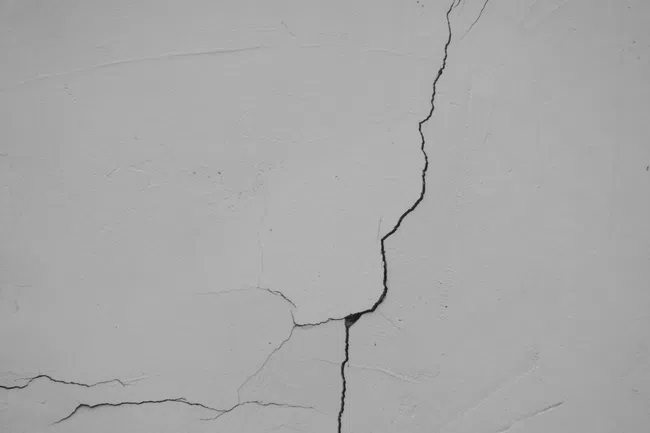 Close-up of multiple cracks on a gray concrete wall showing damage and wear over time