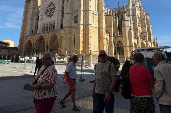 Large Gothic-style cathedral with intricate architecture under a clear blue sky and people walking in front.