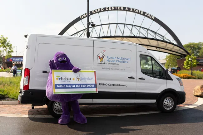 Purple mascot holding sign promoting Telhio Day at the Fair 2026 next to Ronald McDonald House Charities van.