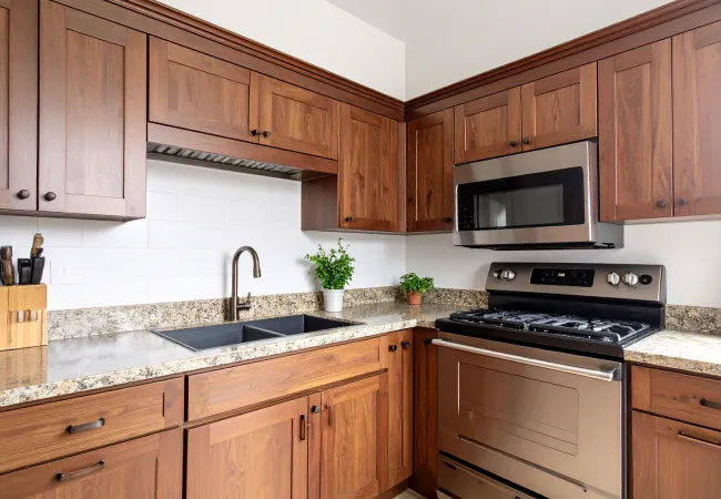 Modern kitchen with wooden cabinets, granite countertops, stainless steel oven, microwave, and a double sink.