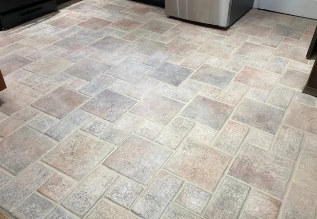 After photo of clean Kitchen floor with light brown and beige textured tiles arranged in a staggered brick pattern.