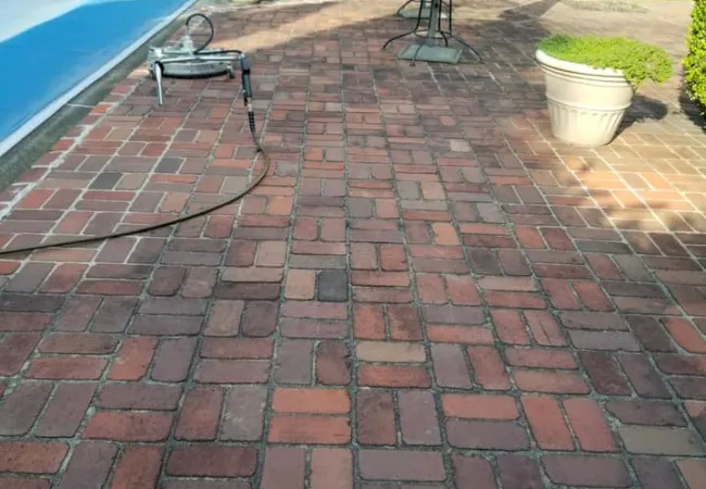 a brick patio with a table and chairs and a pool