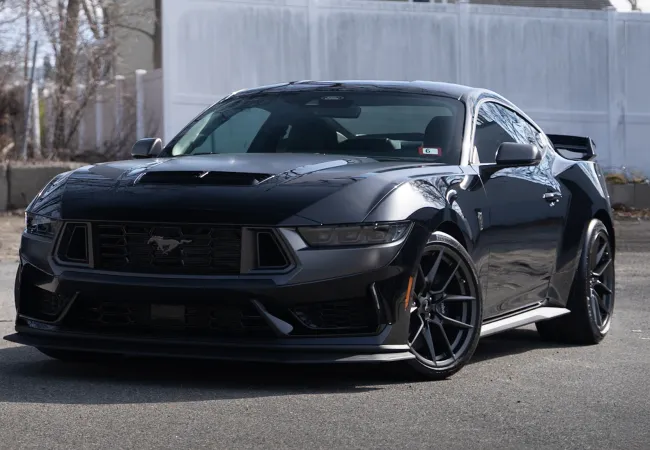 Black Ford Mustang sports car parked outdoors with aggressive styling and aerodynamic features.