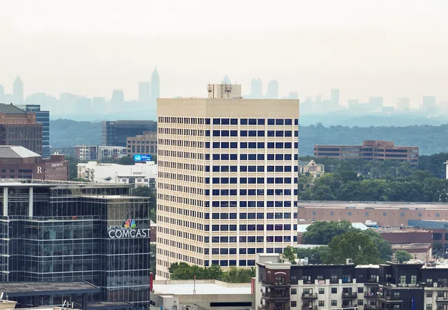 View of urban buildings including Comcast Center with a hazy city skyline in the background under gray sky