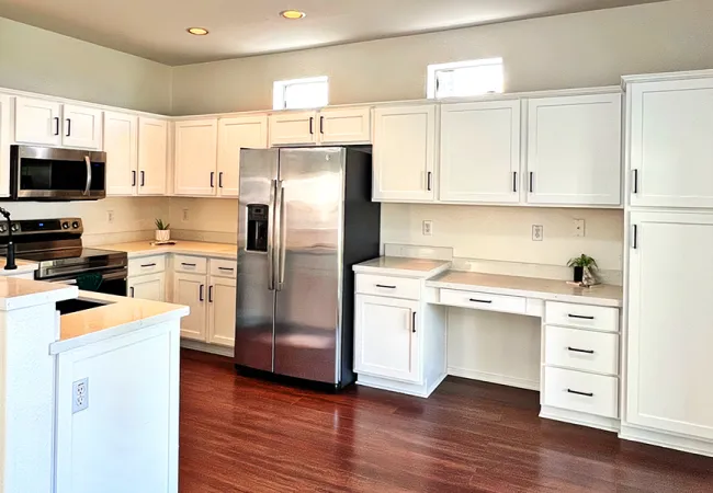 Modern kitchen with white cabinets, stainless steel appliances, hardwood floors, and black hardware accents