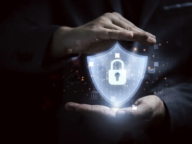 Hands protect glowing shield with padlock symbolizing cybersecurity and data protection
