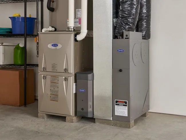 A modern furnace and air conditioning unit in a clean garage space with organized storage shelves.