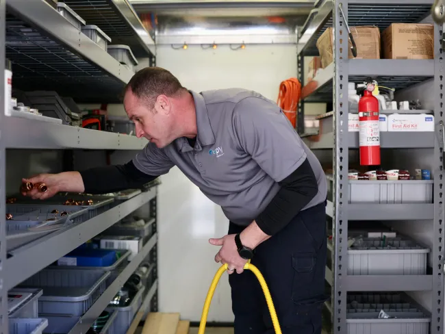 A technician organizing tools and supplies inside a mobile workshop cabinet.