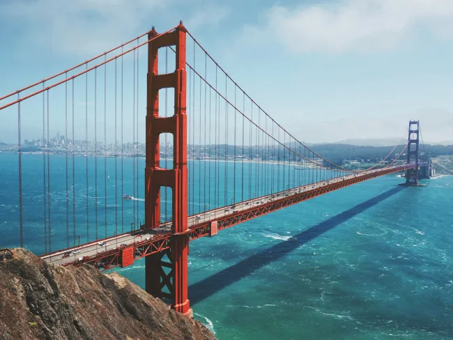 a large red bridge over water with Golden Gate Bridge in the background