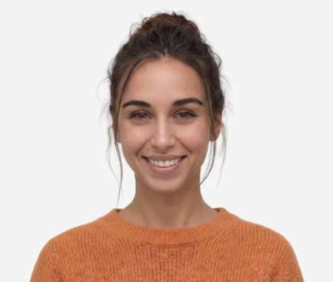 Smiling woman with brown hair in a bun wearing an orange sweater against a light background