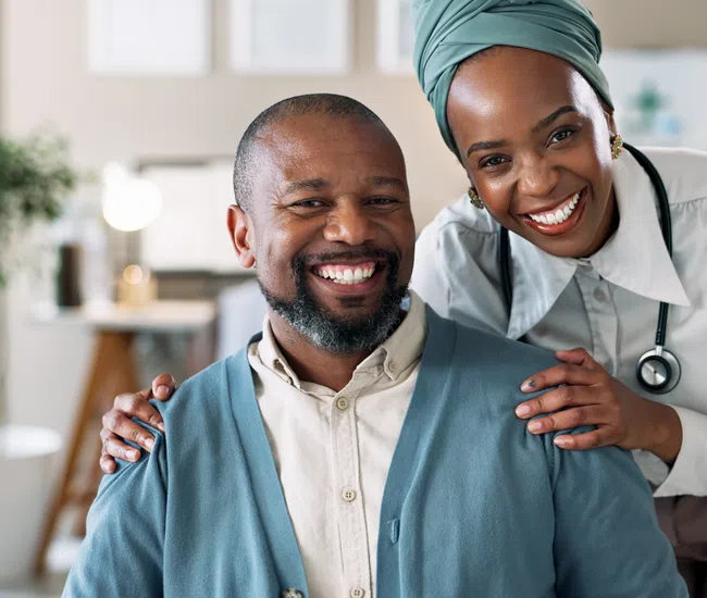Smiling female doctor with stethoscope stands behind a happy male patient in a warm, modern clinic setting