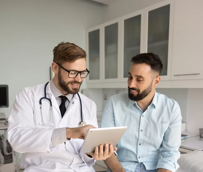 Doctor consulting patient on tablet in modern medical office during a friendly appointment.