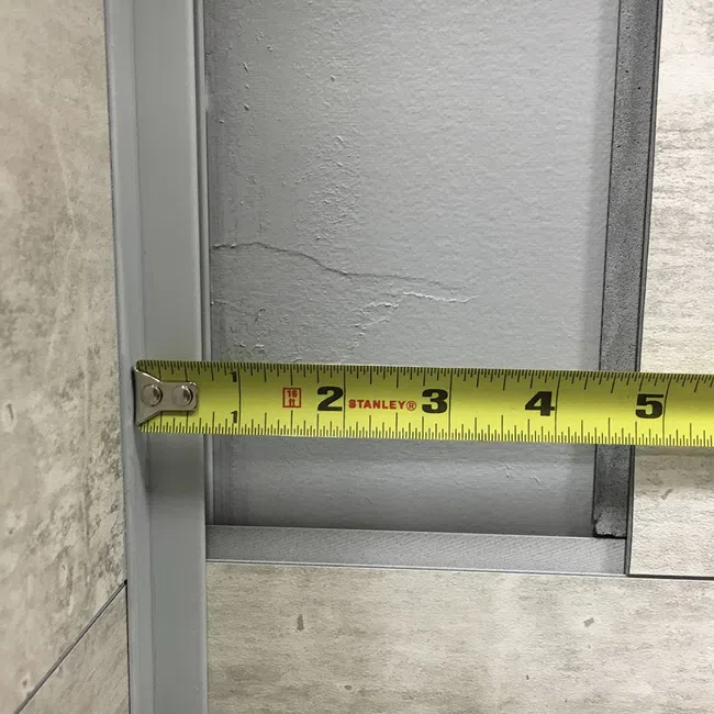 Yellow Stanley tape measure extending across a gray metal surface, measuring approximately 5 inches.