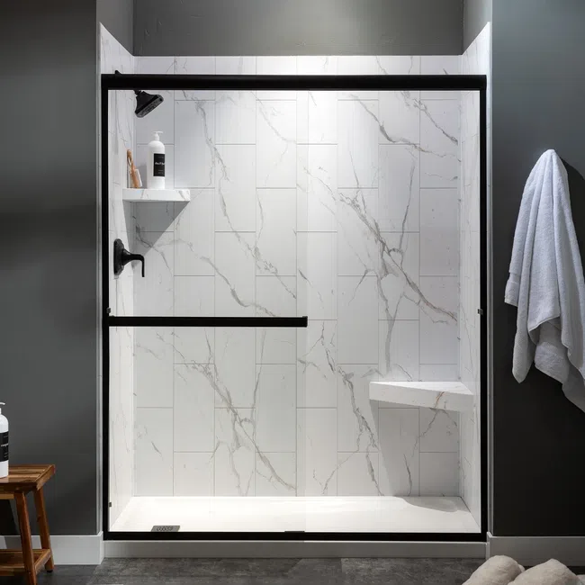 Modern bathroom with a sleek black-framed glass shower, white marble tiles, and neatly hung towels.