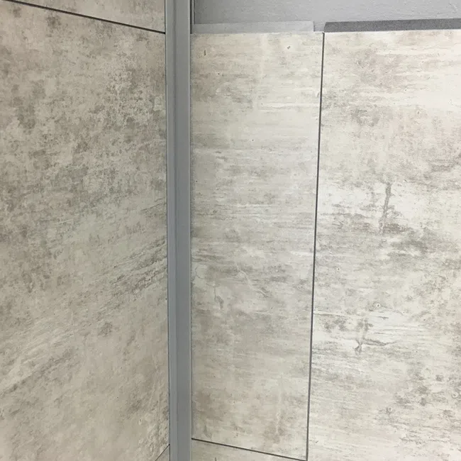 Close-up of stacked large rectangular beige tiles with gray tones and textured surface in a showroom.
