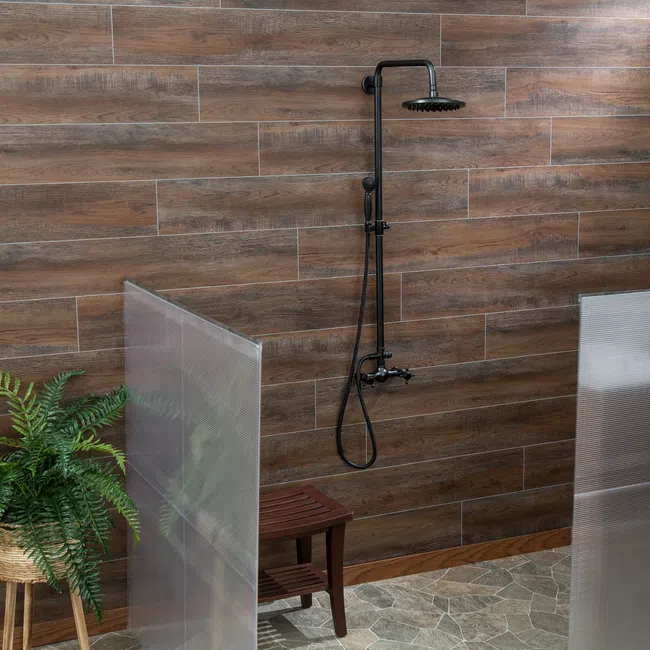 Modern shower setup with black rain showerhead, wooden bench, green plant, and wood-like tile walls.