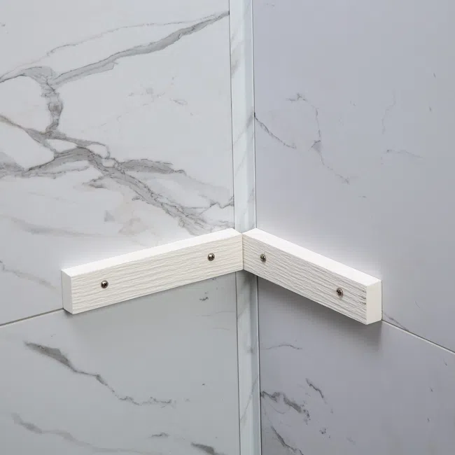 White corner bracket mounted on gray and white marble tiled walls for structural support or decoration.
