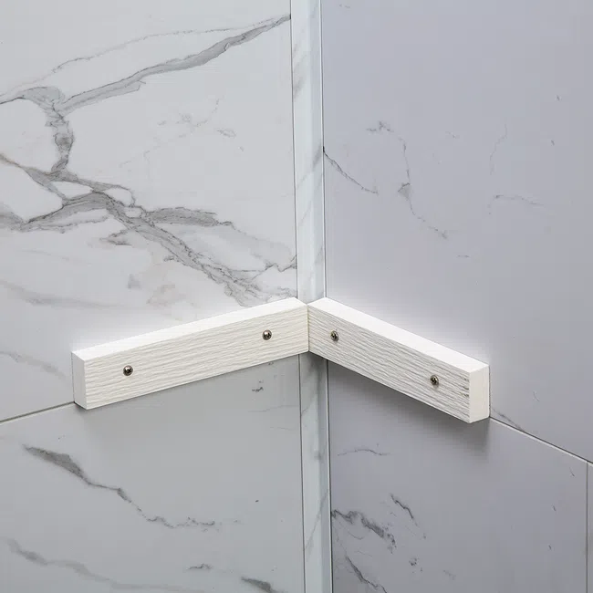 Corner of two marble patterned walls with white wooden support bars attached by screws.