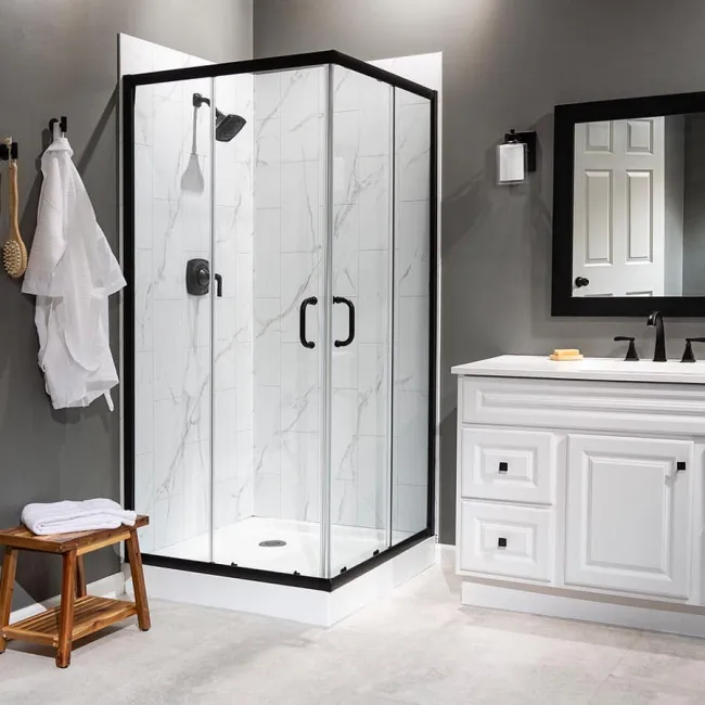 Modern bathroom with glass corner shower, white vanity, black fixtures, and gray walls in minimalist design.