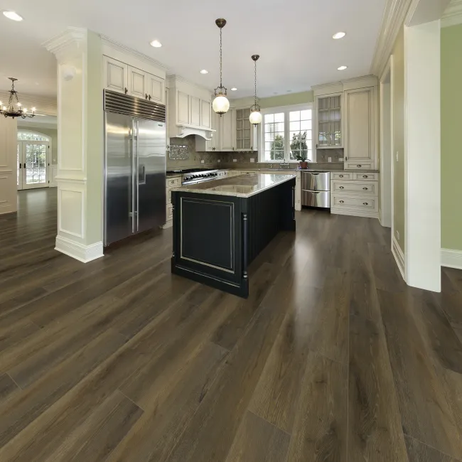 Modern kitchen with dark wood flooring, white cabinetry, black island, stainless appliances, and pendant lighting
