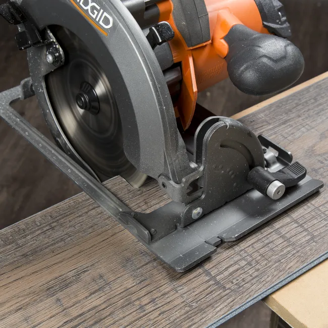 Close-up of a Ridgid circular saw cutting through a piece of wood with visible motion blur on the blade.