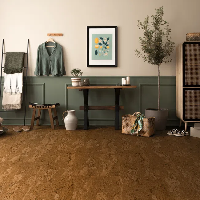 Cozy room with cork flooring, green paneled walls, wooden furniture, potted plant, and woven storage basket.