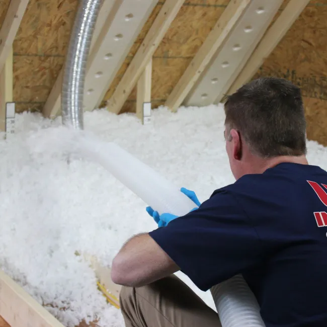 a man installing insulation in an attic