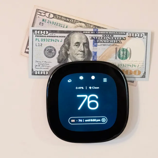 a blue thermostat next to a stack of money