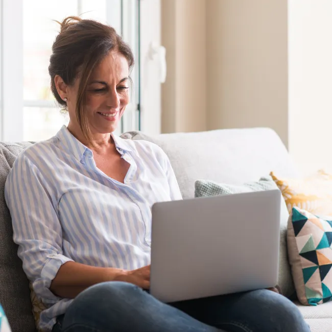 a woman sitting on a couch using a laptop