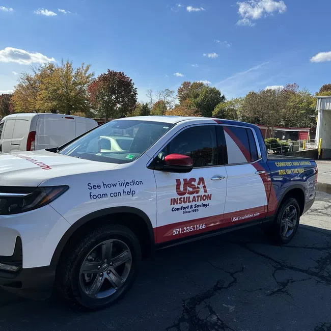 White pickup truck with USA Insulation branding parked in a lot on a sunny day with fall foliage.