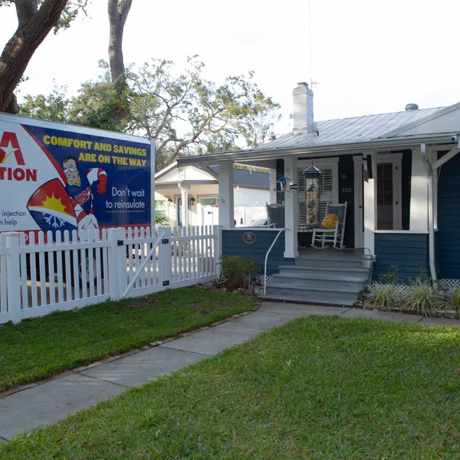 USA Insulation truck parked by a blue house with white trim and a white picket fence during daytime.