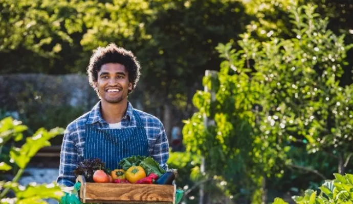 a man holding wood crate of garden produce
