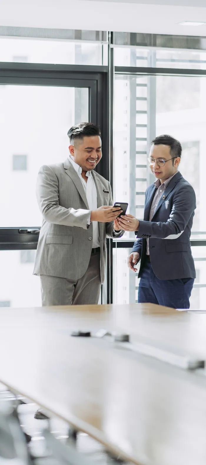 a couple of men in suits looking at a cell phone