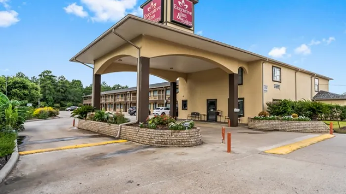 Exterior view of Executive Inn & Suites with covered entrance and parking under blue sky with clouds.