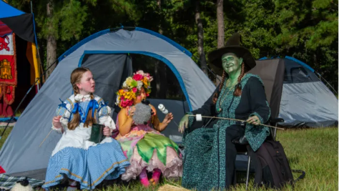 a group of women sitting in chairs outside by a tent