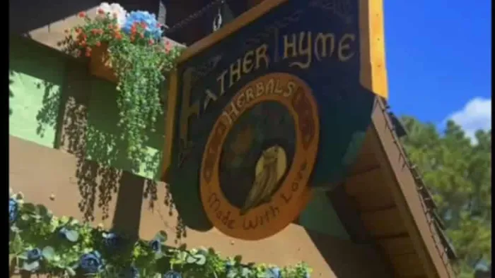 Rustic outdoor shop sign for Father Thyme Herbals with greenery and blue sky background