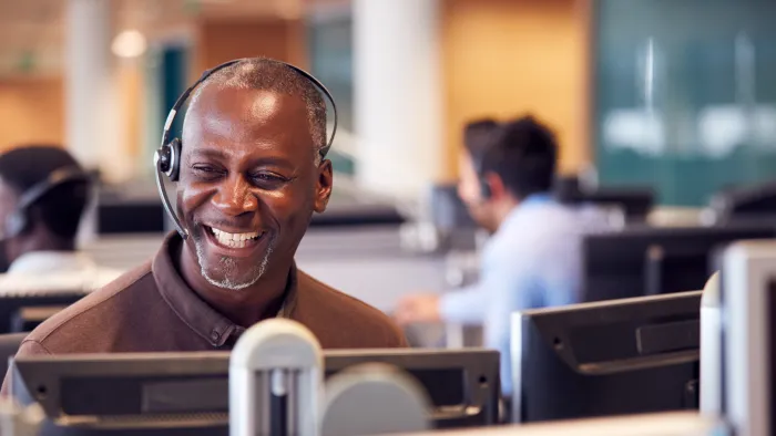 Smiling customer service representative wearing headset working at a computer in modern office environment