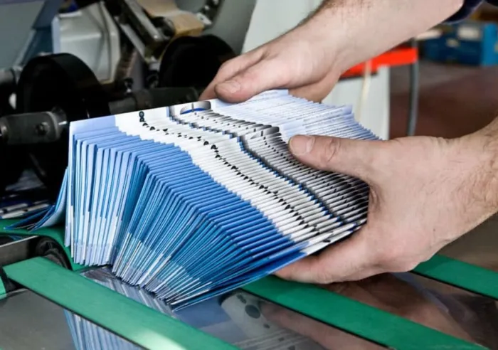 A stack of printed brochures exiting the folding machine