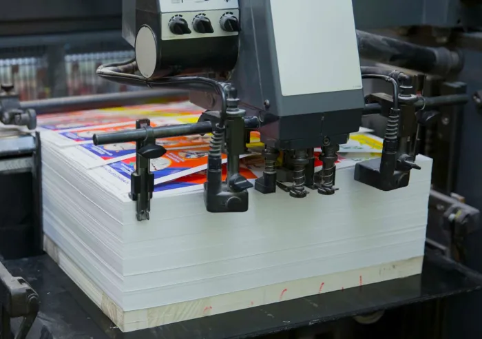 Commercial printing press producing colorful printed sheets.