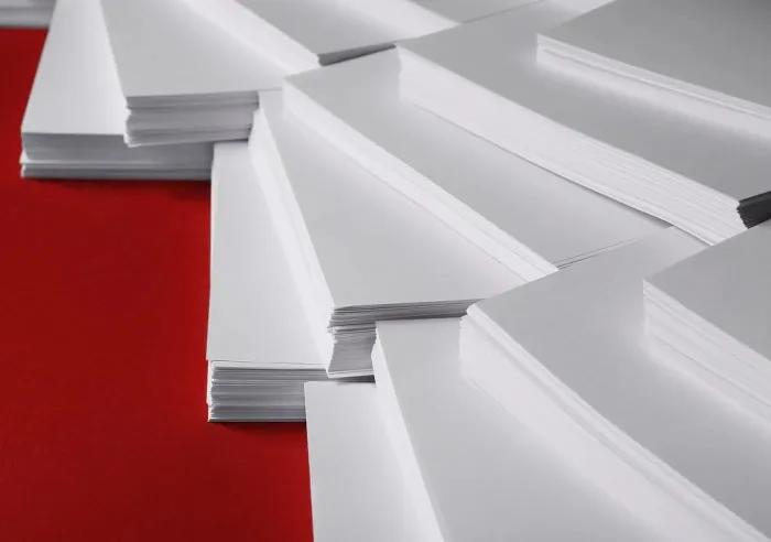 Stacks of white paper on a red surface in various orientations and layers.