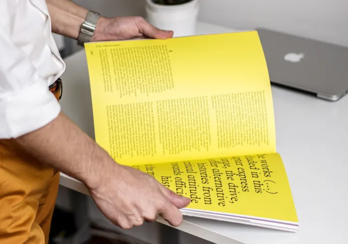 A person reading through a large book with yellow pages